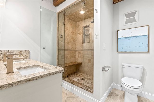 a bathroom with a granite countertop sink a toilet and shower