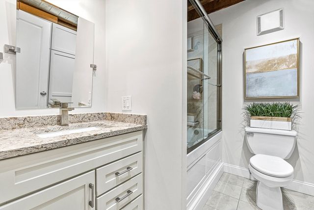 a bathroom with a granite countertop sink toilet and painting on the wall