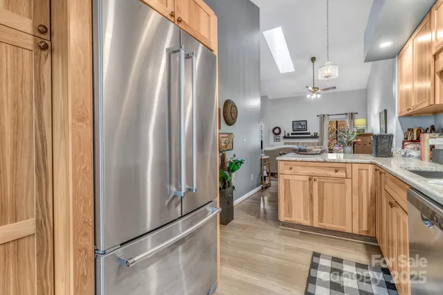 a kitchen with stainless steel appliances granite countertop a refrigerator a sink and white cabinets