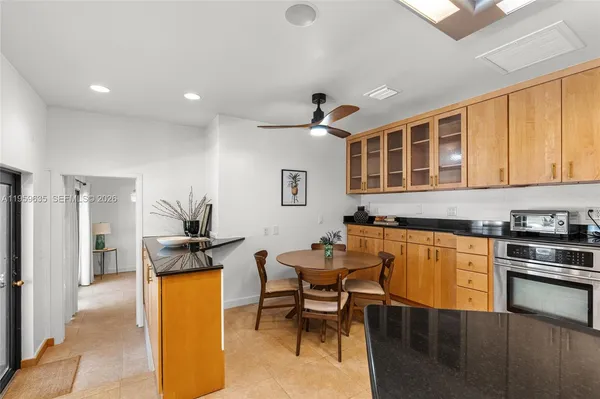 a kitchen with stainless steel appliances granite countertop a stove top oven a sink a dining table and chairs with wooden floor