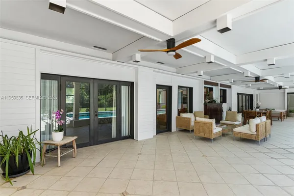 a living room with patio furniture and potted plants