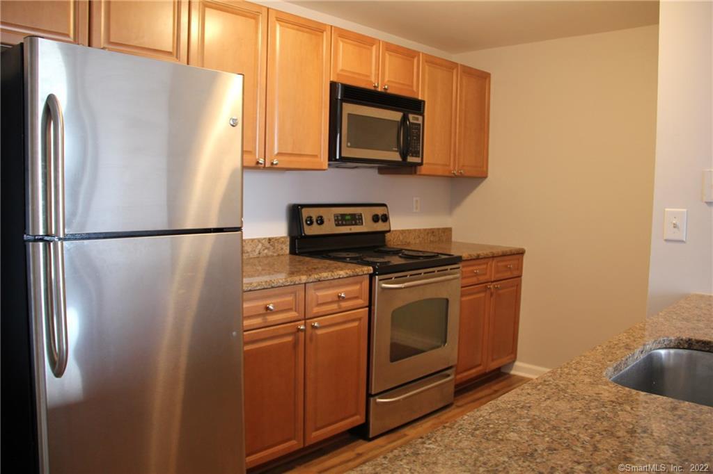 300 Broad Street, Unit 607 Stamford, CT 06901 - Photo 6 of 25 a kitchen with stainless steel appliances granite countertop a refrigerator stove and microwave