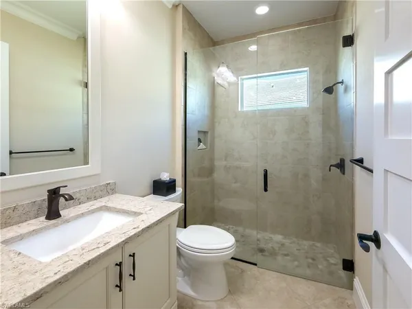 a bathroom with a granite countertop sink a toilet and shower