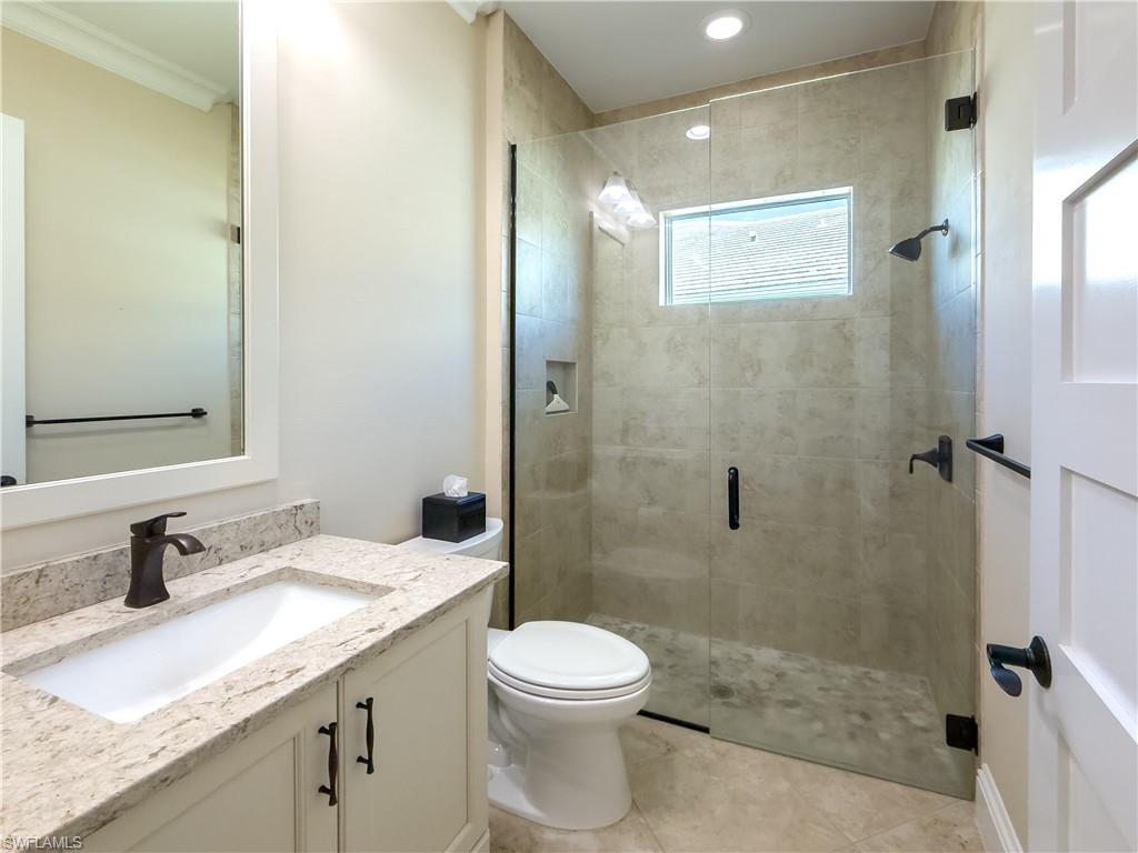 6399 Negril Isle Drive Naples, FL 34113 - Photo 18 of 33 a bathroom with a granite countertop sink a toilet and shower