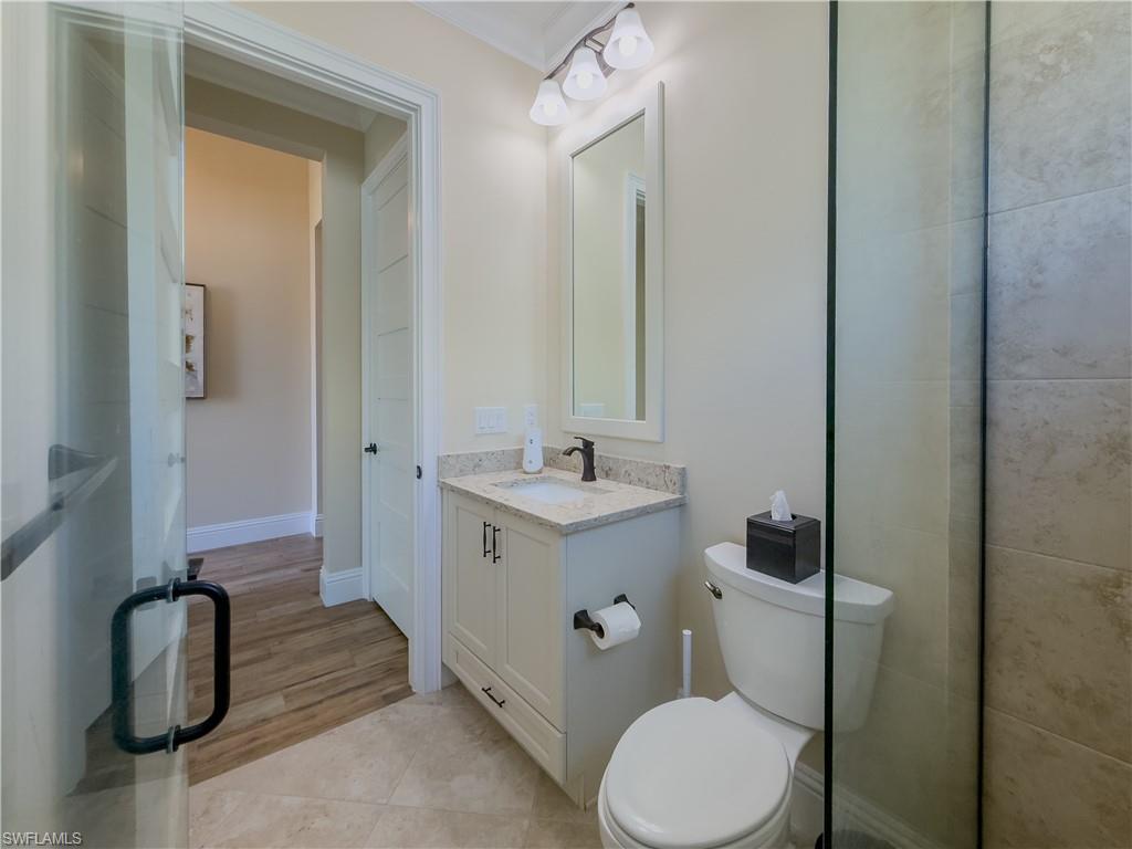 6399 Negril Isle Drive Naples, FL 34113 - Photo 19 of 33 a bathroom with a toilet sink vanity and mirror