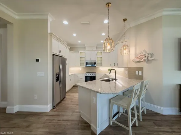 a large kitchen with stainless steel appliances kitchen island granite countertop a table chairs and a refrigerator