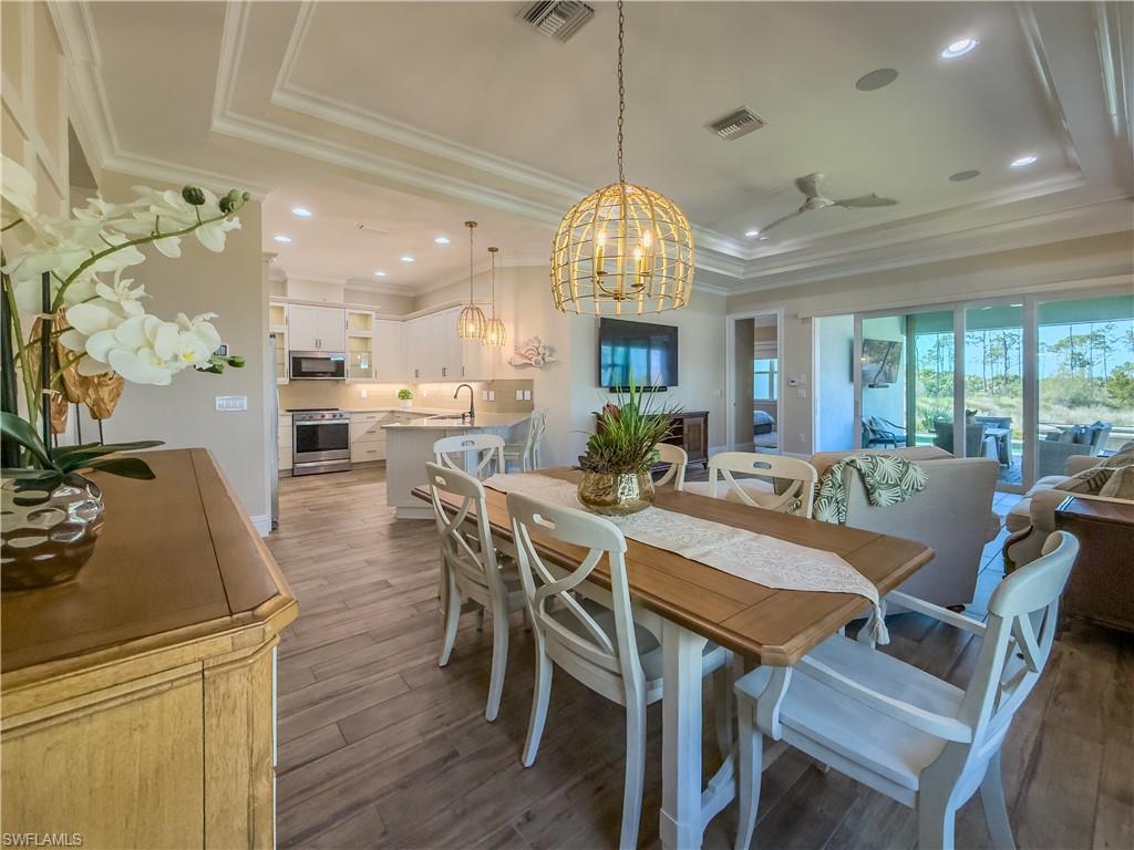 6399 Negril Isle Drive Naples, FL 34113 - Photo 9 of 33 a view of a dining room with furniture a chandelier and wooden floor