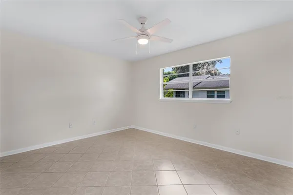 an empty room with a ceiling fan and window