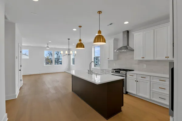 a kitchen with kitchen island granite countertop a sink a stove and cabinets