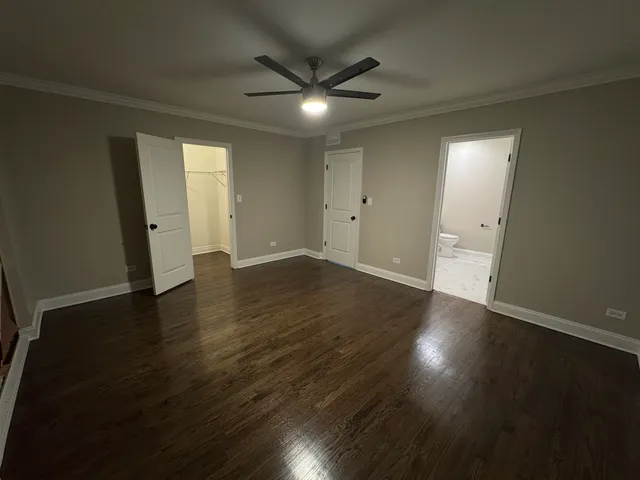 an empty room with wooden floor and a ceiling fan