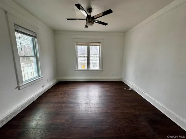 an empty room with wooden floor and windows with curtains