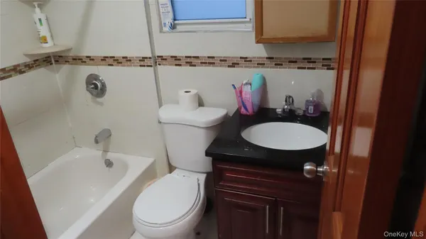 a bathroom with a granite countertop toilet sink and mirror