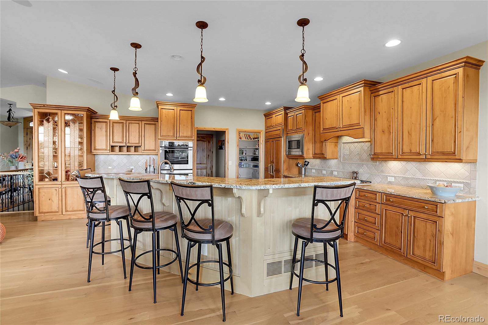 1007 Nob Hill Road Evergreen, CO 80439 - Photo 11 of 48 a kitchen with stainless steel appliances a dining table chairs sink and white cabinets
