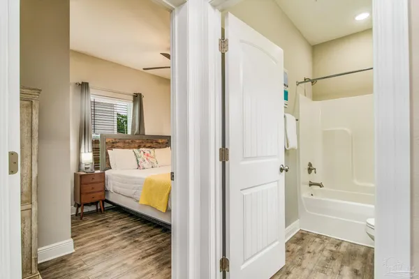 a bathroom with a tub shower and hardwood floor