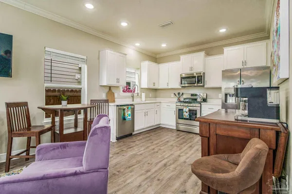 a kitchen with stainless steel appliances granite countertop a dining table chairs refrigerator sink and cabinets