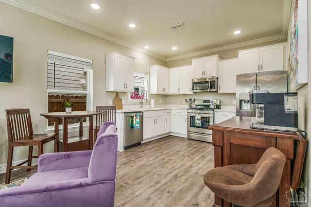 a kitchen with stainless steel appliances granite countertop a dining table chairs refrigerator sink and cabinets