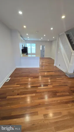 a view of kitchen and empty room with wooden floor