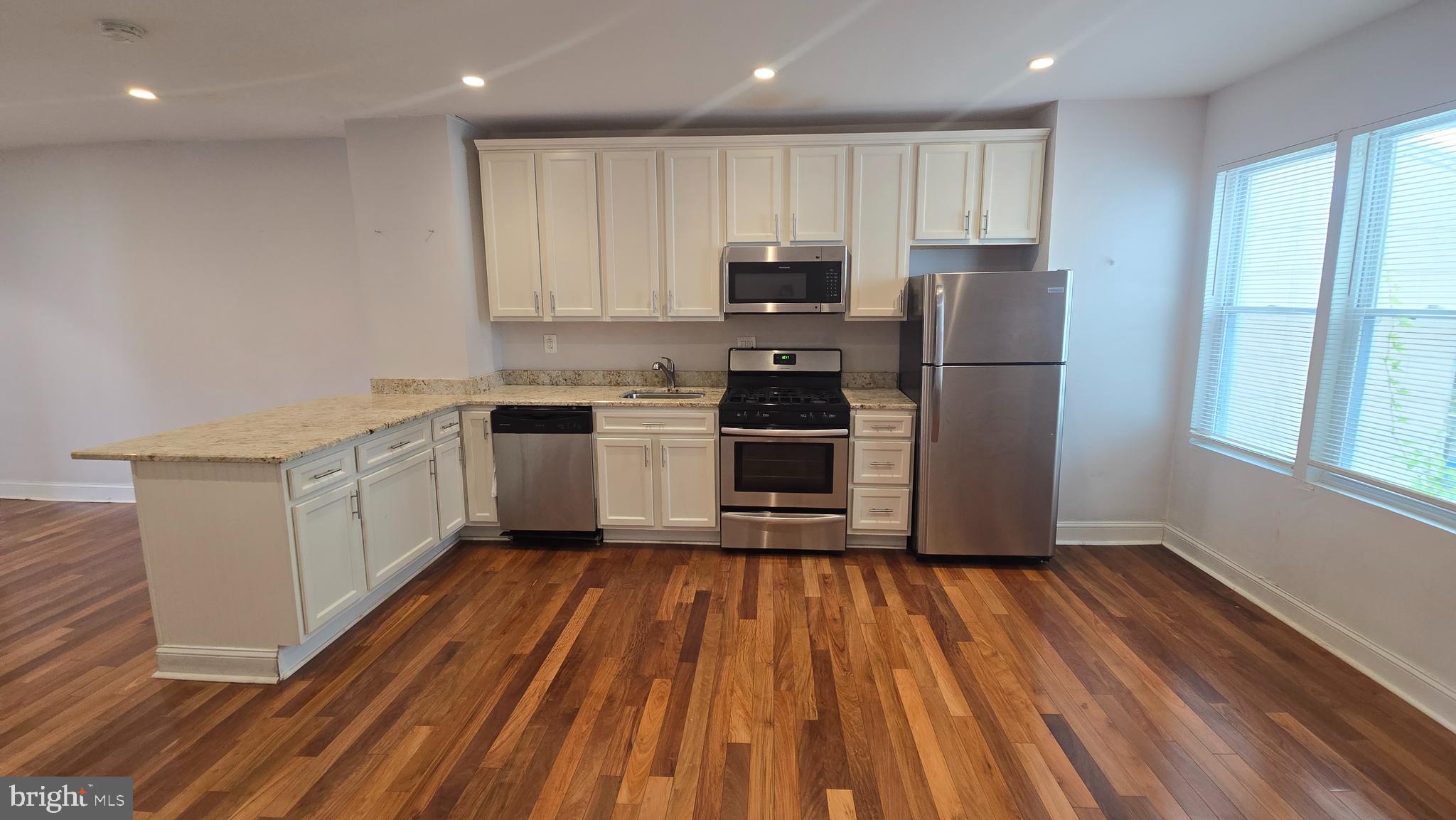 6814 Harford Road Baltimore, MD 21234 - Photo 10 of 27 a kitchen with wooden floors stainless steel appliances a sink and cabinets