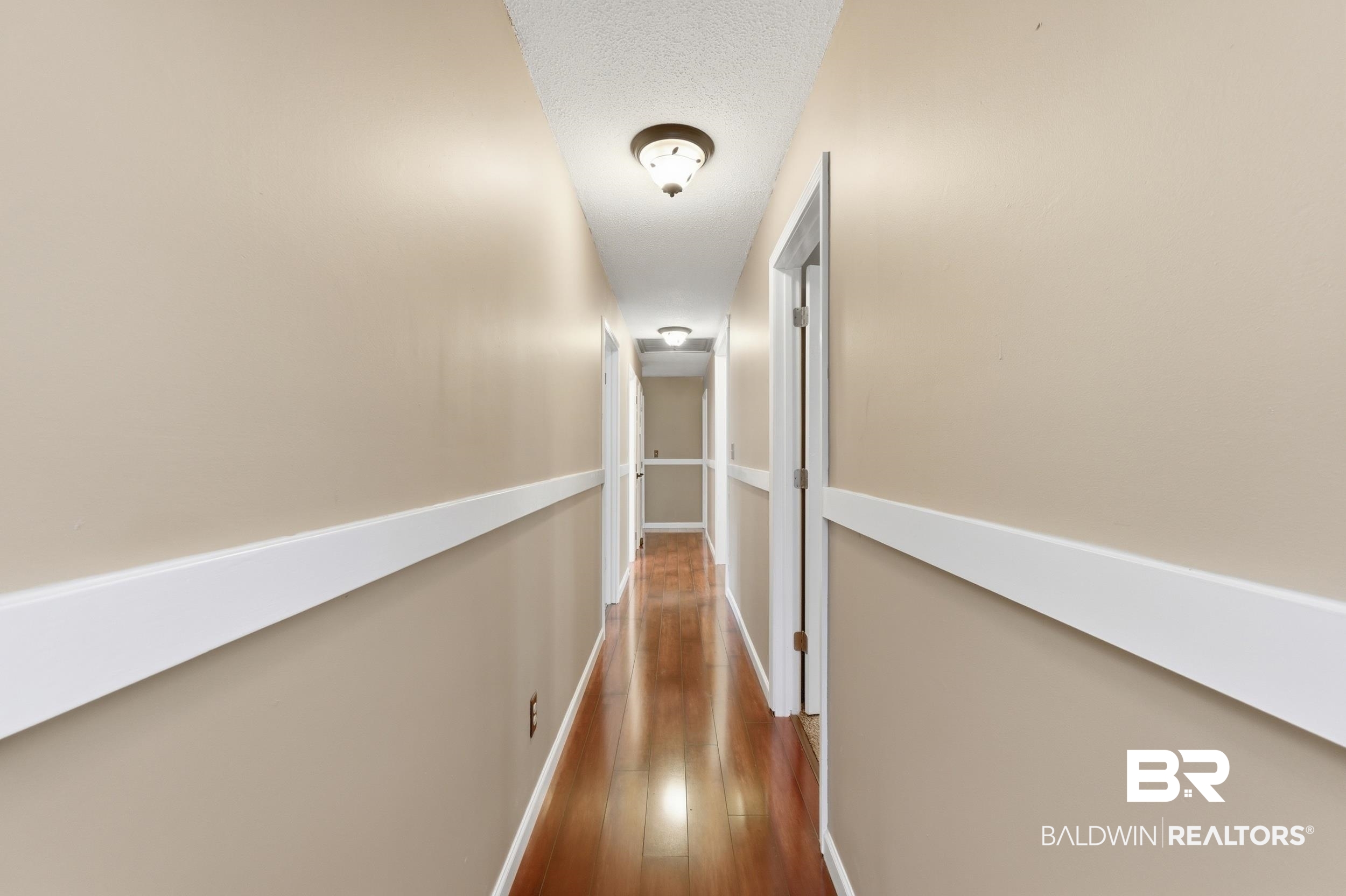 51620 Robert White Road Bay Minette, AL 36507 - Photo 39 of 81 Hallway with wood-finish flooring, neutral wall paint, white chair rail molding, and multiple flush-mount ceiling lights