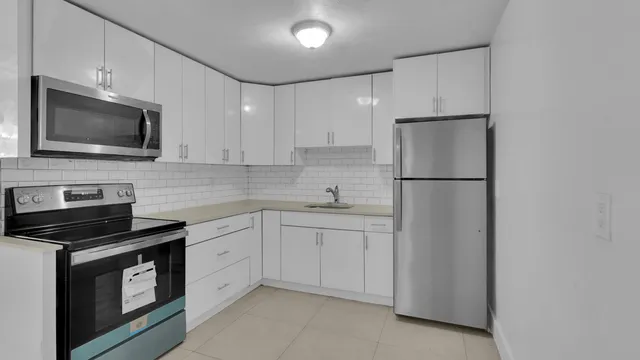 a kitchen with white cabinets and black appliances