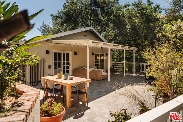 a patio with a table and chairs and potted plants