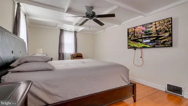 a bedroom with a bed a wall painting and a potted plant