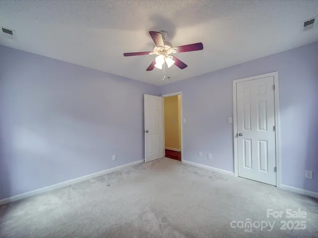 a view of an empty room and chandelier fan