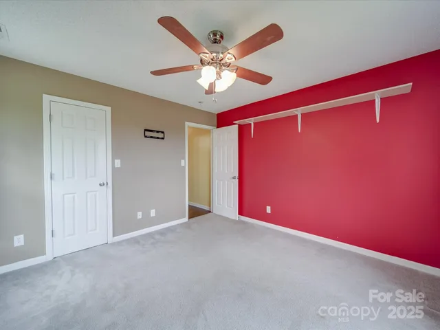 a view of an empty room with window and a ceiling fan