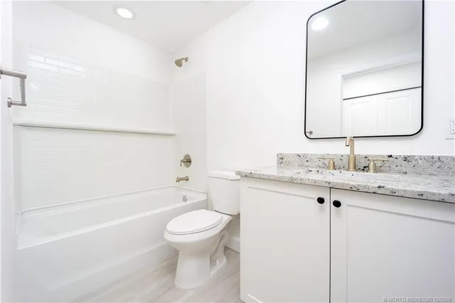 a bathroom with a granite countertop toilet sink and mirror