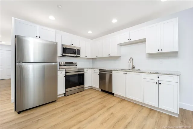 a kitchen with cabinets stainless steel appliances and wooden floor