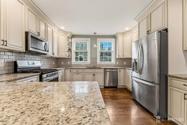 a kitchen with stainless steel appliances granite countertop a refrigerator a sink a stove a microwave and cabinets