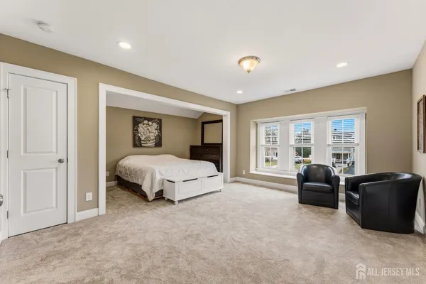 a spacious bedroom with a large bed and a flat tv screen on dresser