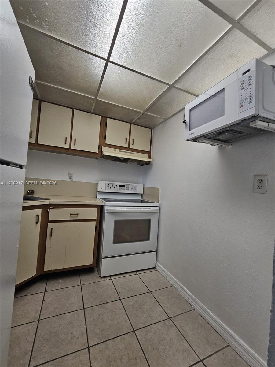 4550 Northwest 9th Street, Unit 217E Miami, FL 33126 - Photo 11 of 14 a kitchen with stainless steel appliances granite countertop a stove a sink and a microwave