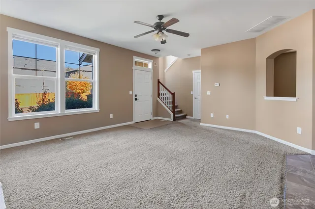 an empty room with windows and chandelier fan