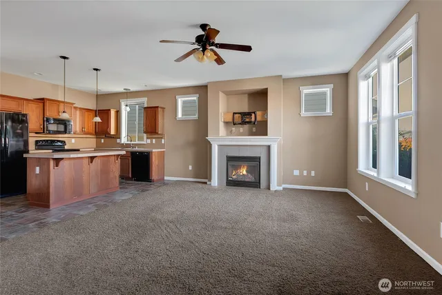 a view of kitchen with stainless steel appliances granite countertop a stove top oven a sink a refrigerator and a fireplace