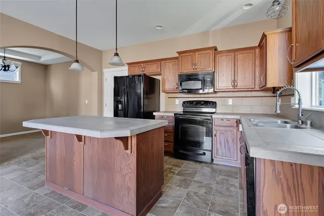 a kitchen with stainless steel appliances a stove a sink dishwasher a refrigerator with a dining table and chairs