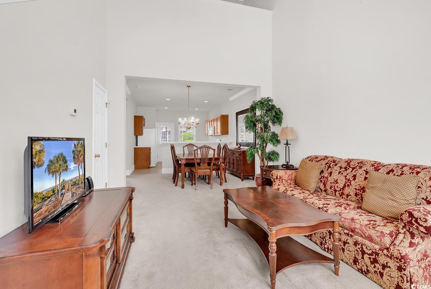 101 Culpepper Way, Unit 1006 Myrtle Beach, SC 29579 - Photo 3 of 40 Living area featuring a chandelier, light colored carpet, a towering ceiling, and baseboards