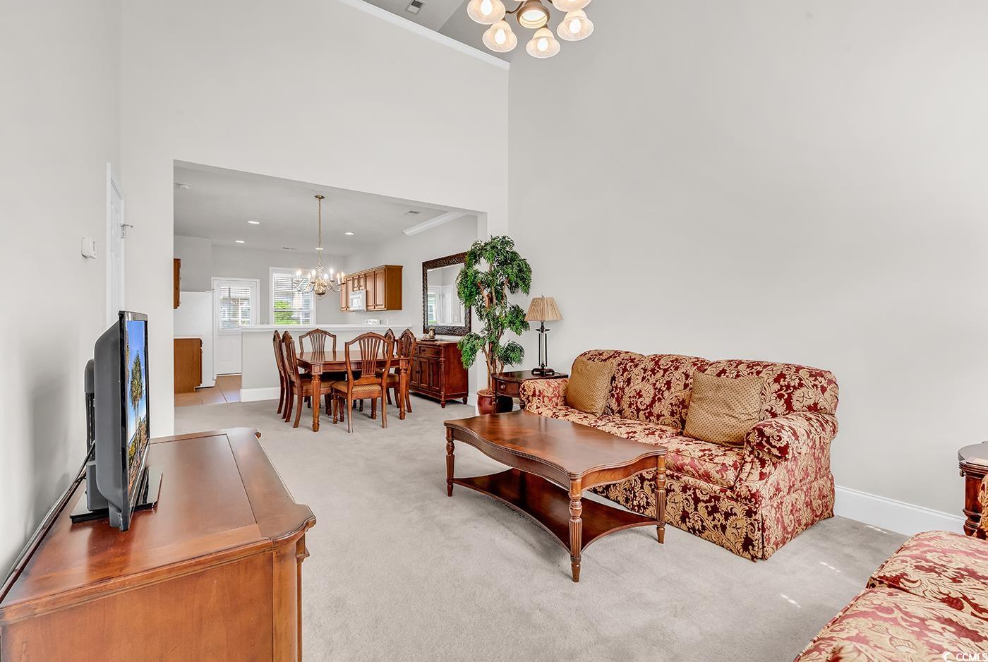 101 Culpepper Way, Unit 1006 Myrtle Beach, SC 29579 - Photo 4 of 40 Living area with a chandelier, light carpet, baseboards, and a towering ceiling