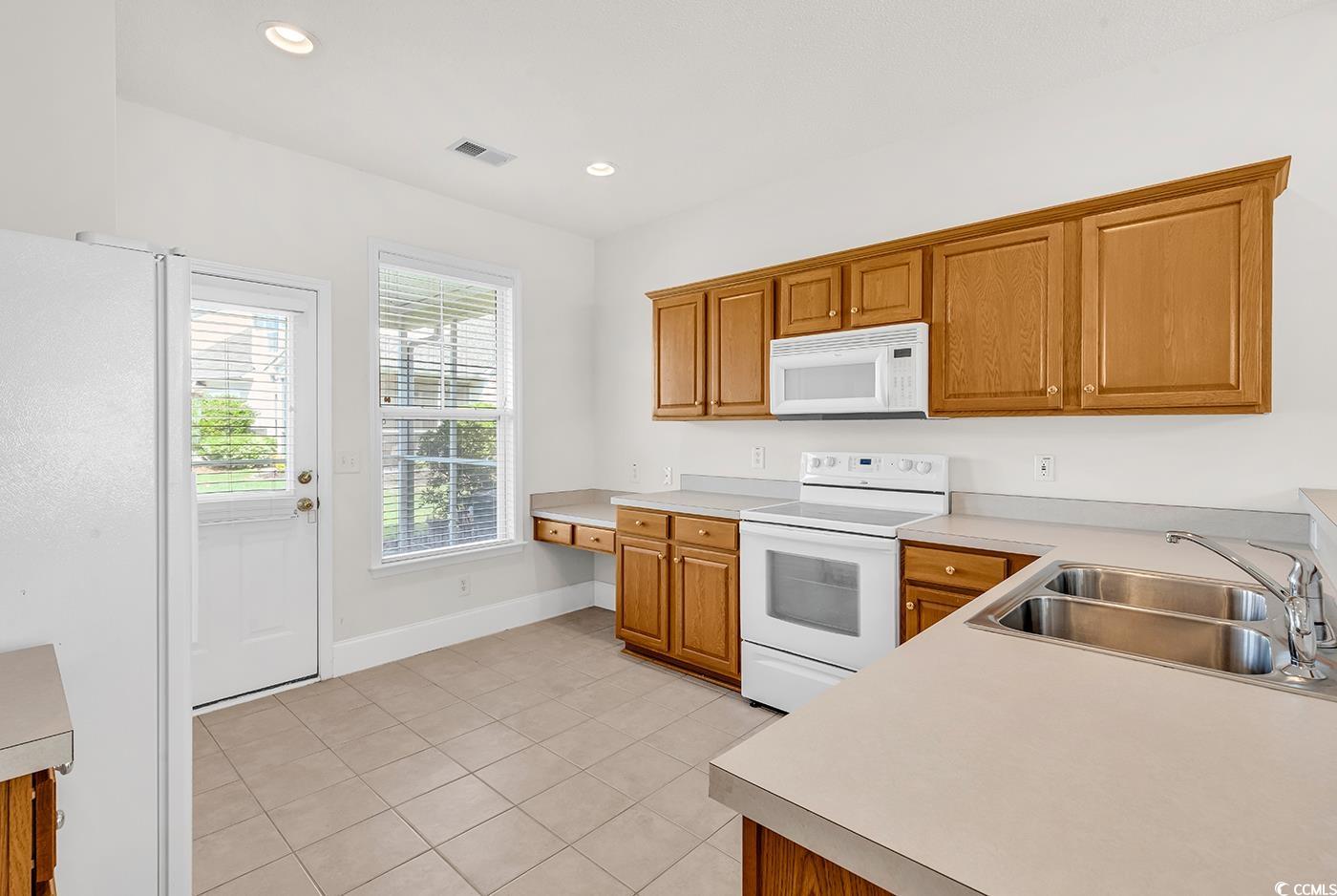 101 Culpepper Way, Unit 1006 Myrtle Beach, SC 29579 - Photo 8 of 40 Kitchen featuring white appliances, a sink, light tile patterned floors, light countertops, and baseboards