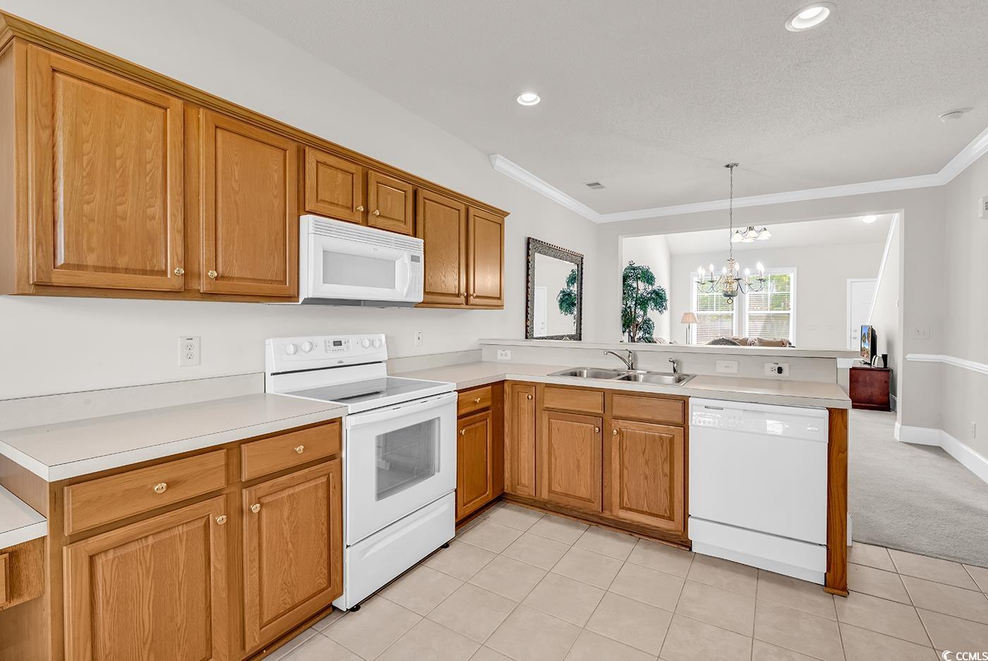 101 Culpepper Way, Unit 1006 Myrtle Beach, SC 29579 - Photo 9 of 40 Kitchen with white appliances, a peninsula, a sink, ornamental molding, and a chandelier