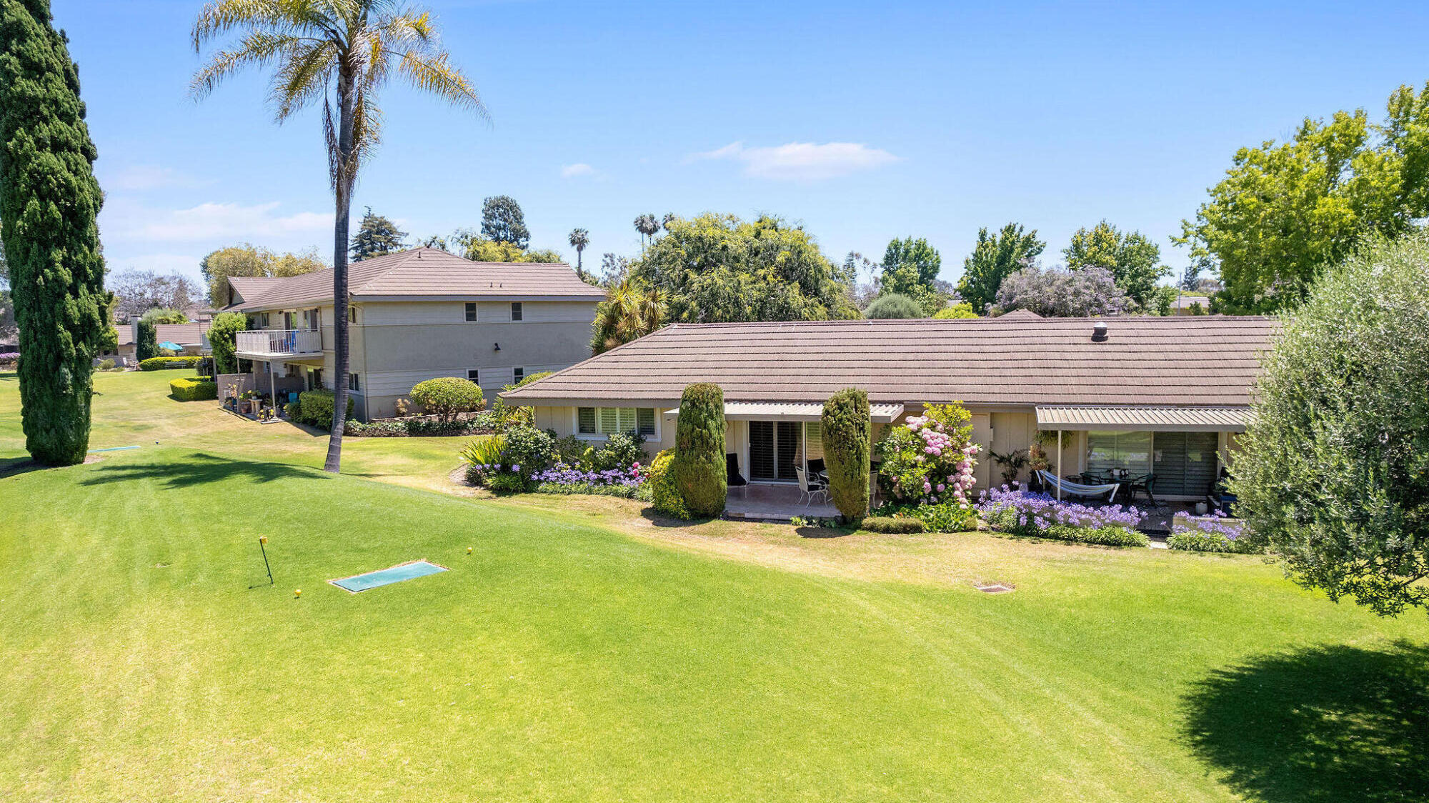 5822 Encina Road, Unit 2 Santa Barbara, CA 93117 - Photo 18 of 42 a view of a house with floor to ceiling windows and a table and chairs under an umbrella