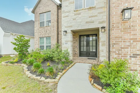a kitchen with stainless steel appliances granite countertop a stove a sink a refrigerator and white cabinets with wooden floor