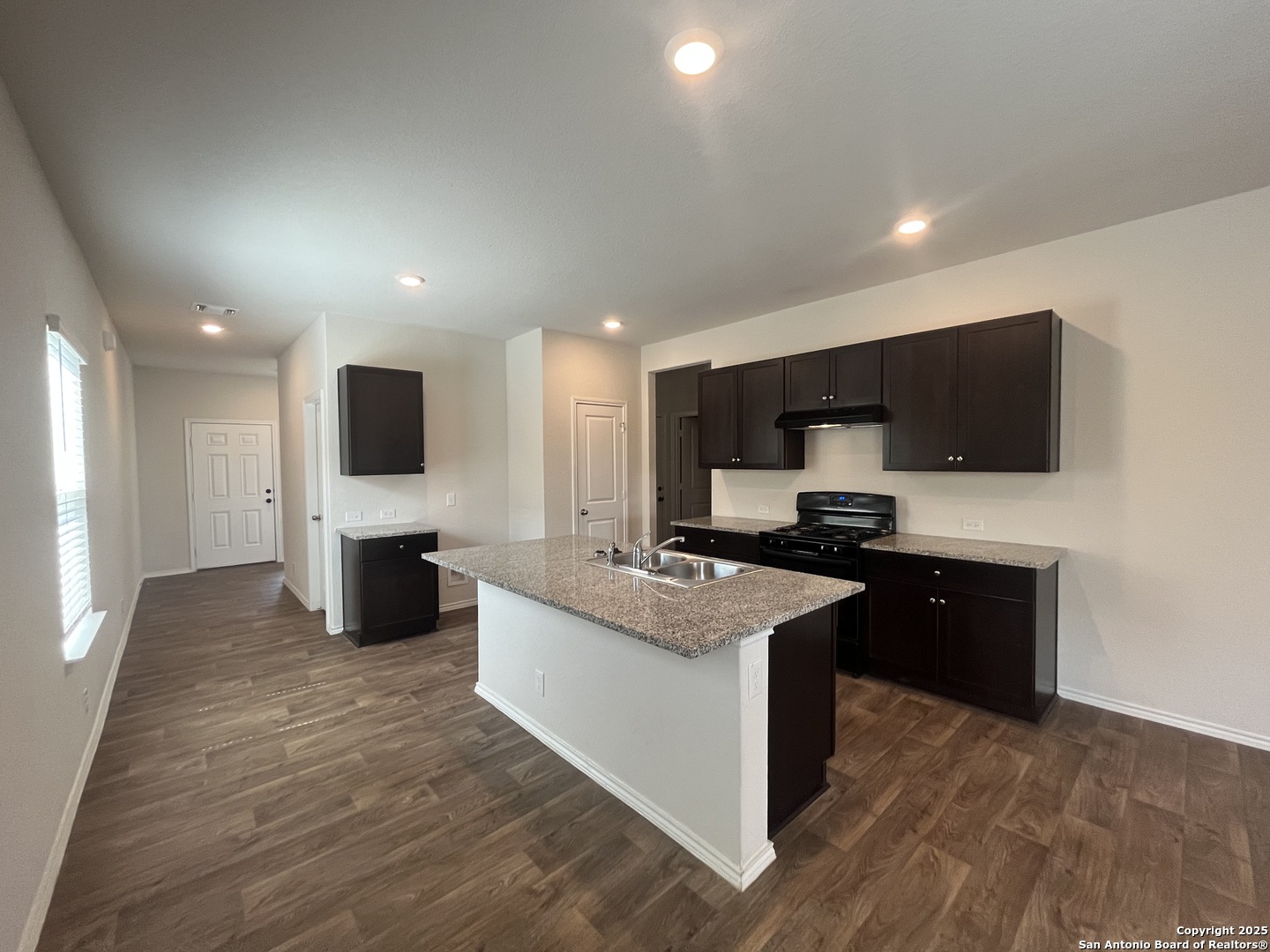141 Middle Grn Loop Floresville, TX 78114 - Photo 2 of 29 a kitchen with stainless steel appliances kitchen island granite countertop a stove top oven and sink