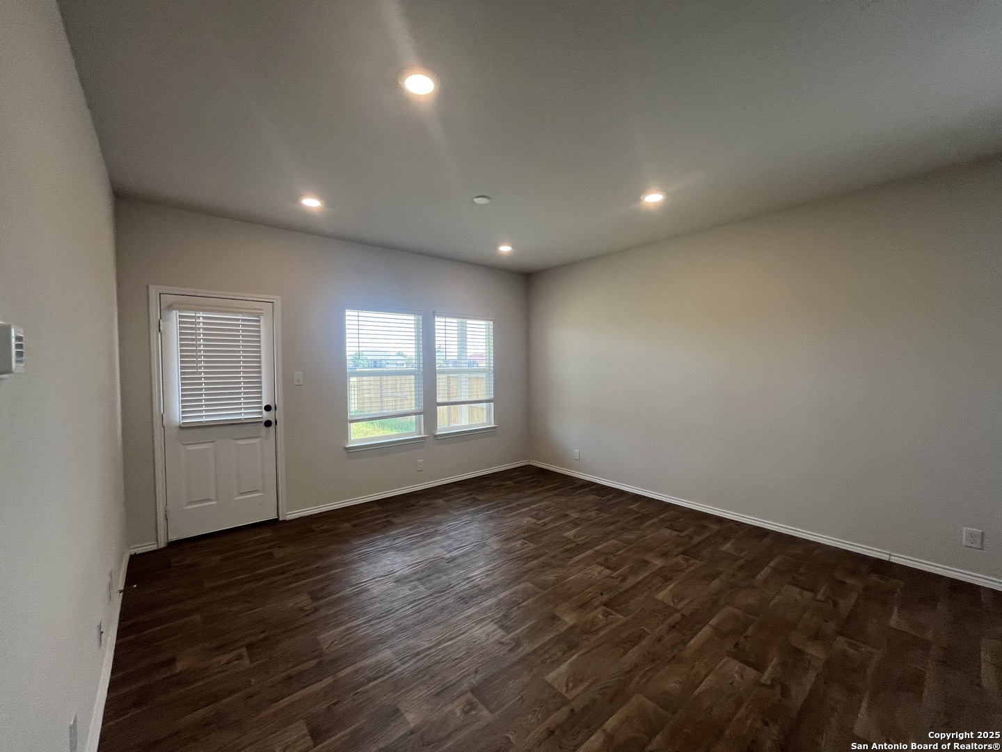 141 Middle Grn Loop Floresville, TX 78114 - Photo 8 of 29 an empty room with wooden floor and windows