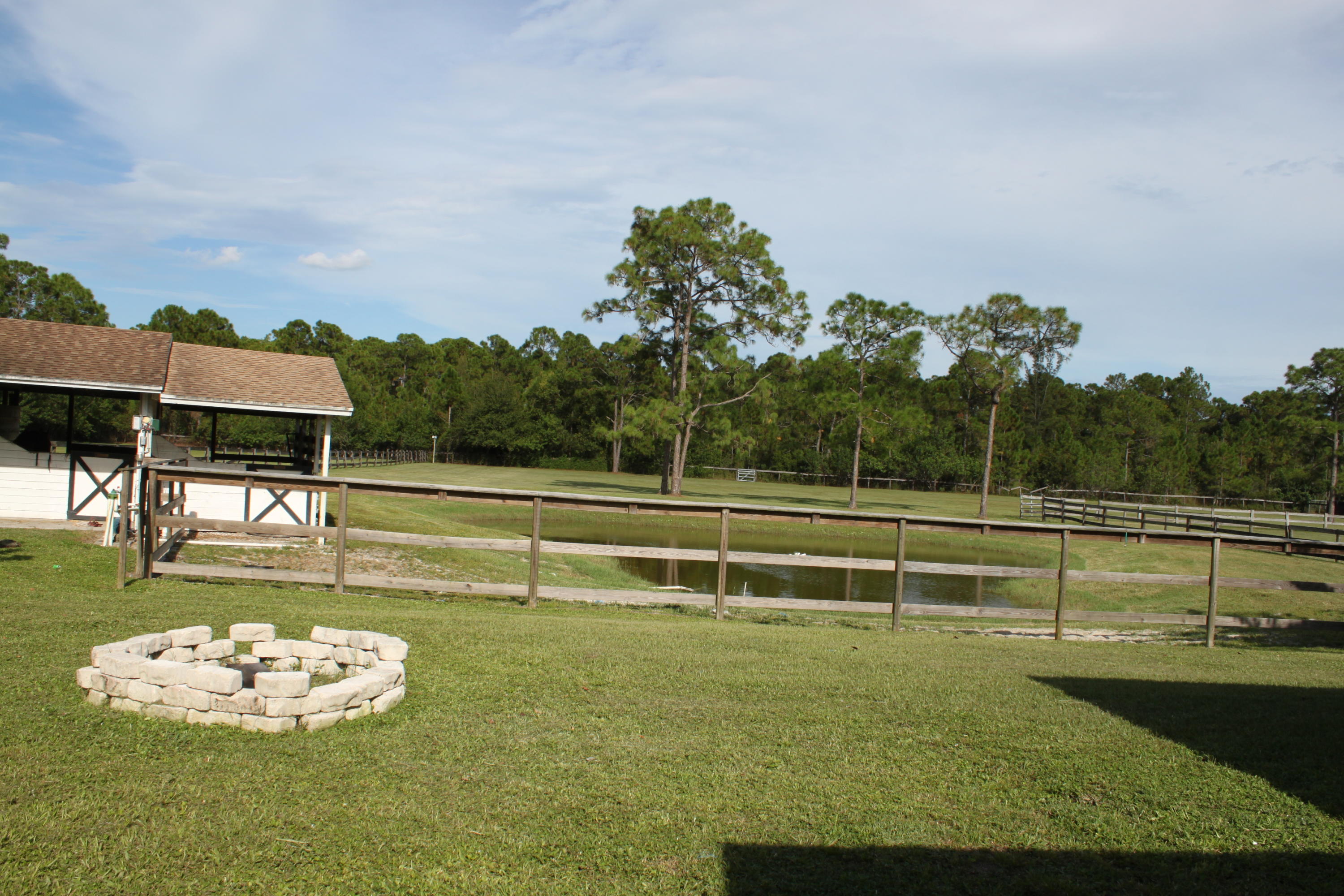 3840 Dellwood Road Loxahatchee, FL 33470 - Photo 31 of 60 a view of a swimming pool with a lawn chairs under an umbrella