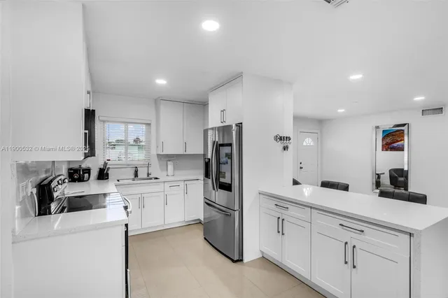 a kitchen with white cabinets and refrigerator