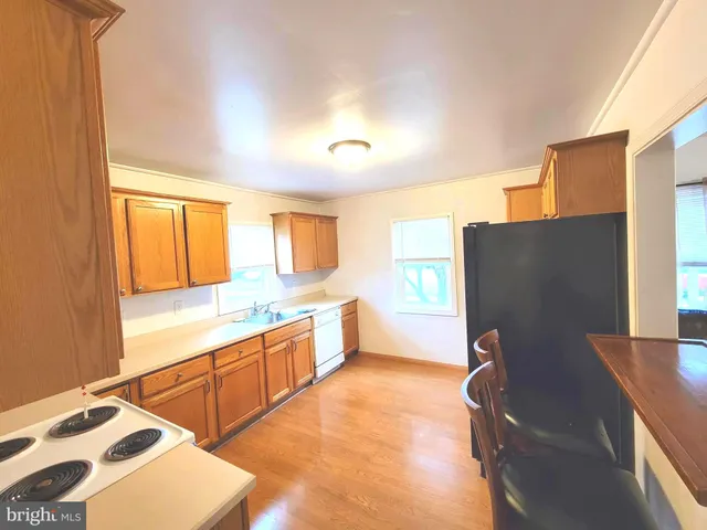 a kitchen with stainless steel appliances granite countertop a refrigerator a sink dishwasher and a stove with wooden floor