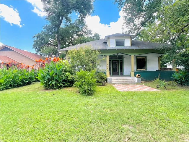 a view of a house with a yard and potted plants