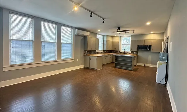 a large white kitchen with wooden floor and a refrigerator