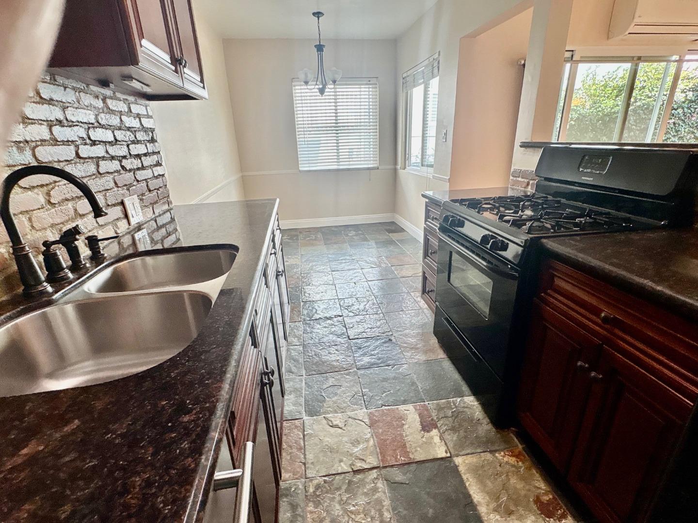 11719 Mayfield Avenue, Unit 1 Los Angeles, CA 90049 - Photo 16 of 28 a kitchen with granite countertop a sink and a stove
